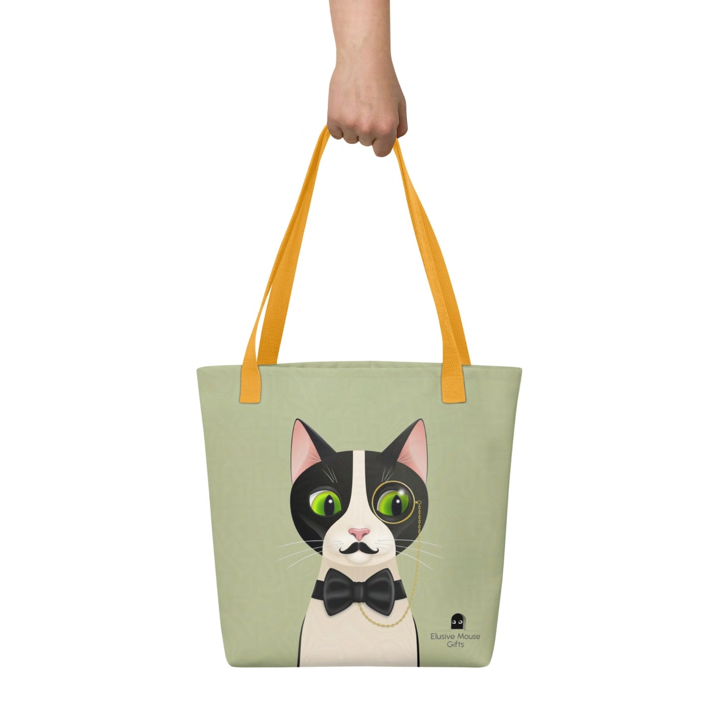 Alfred tote bag shown being carried by hand with the full cat illustration visible, against a sage green background