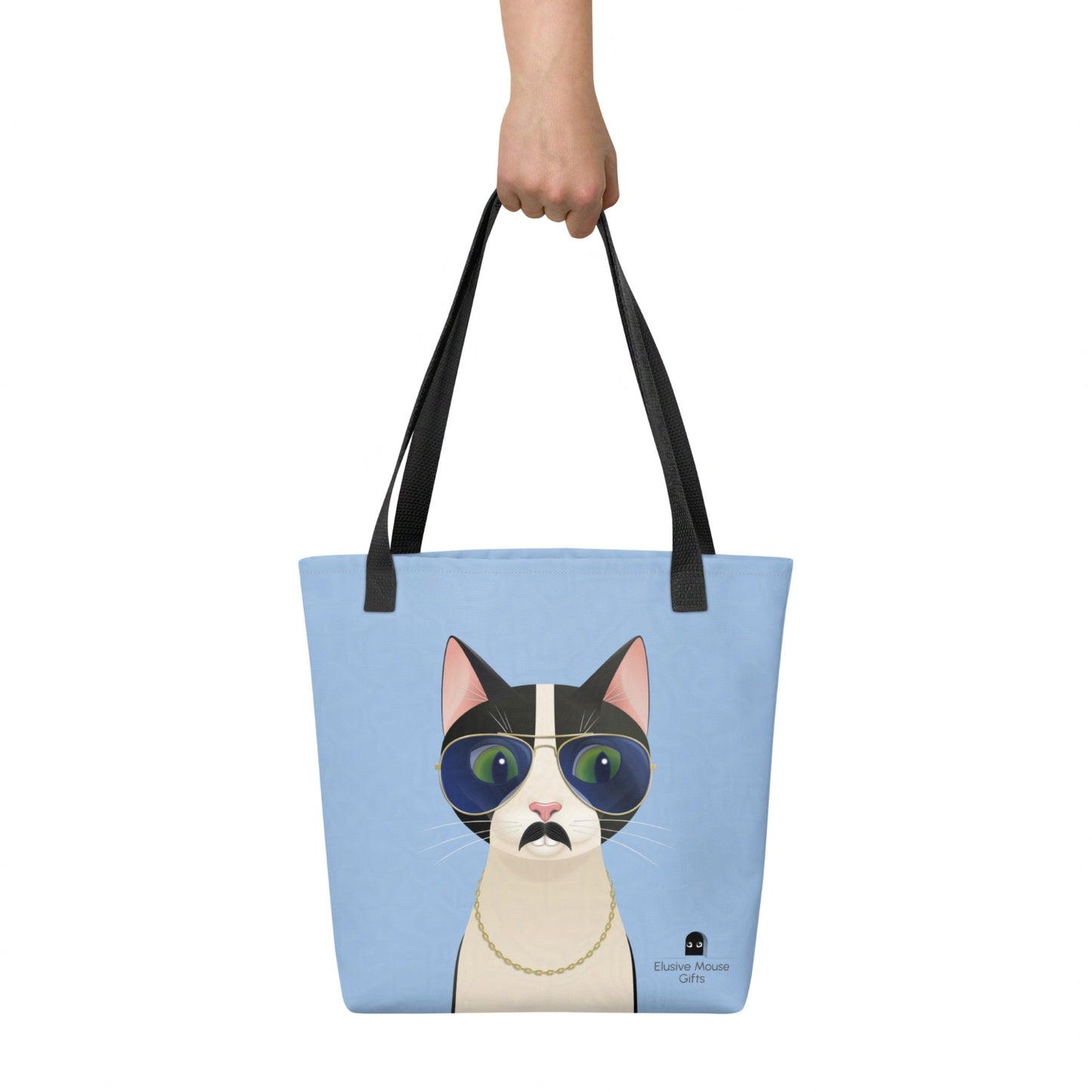 Freddie tote bag held by hand, showing the full playful cat illustration against a blue background.