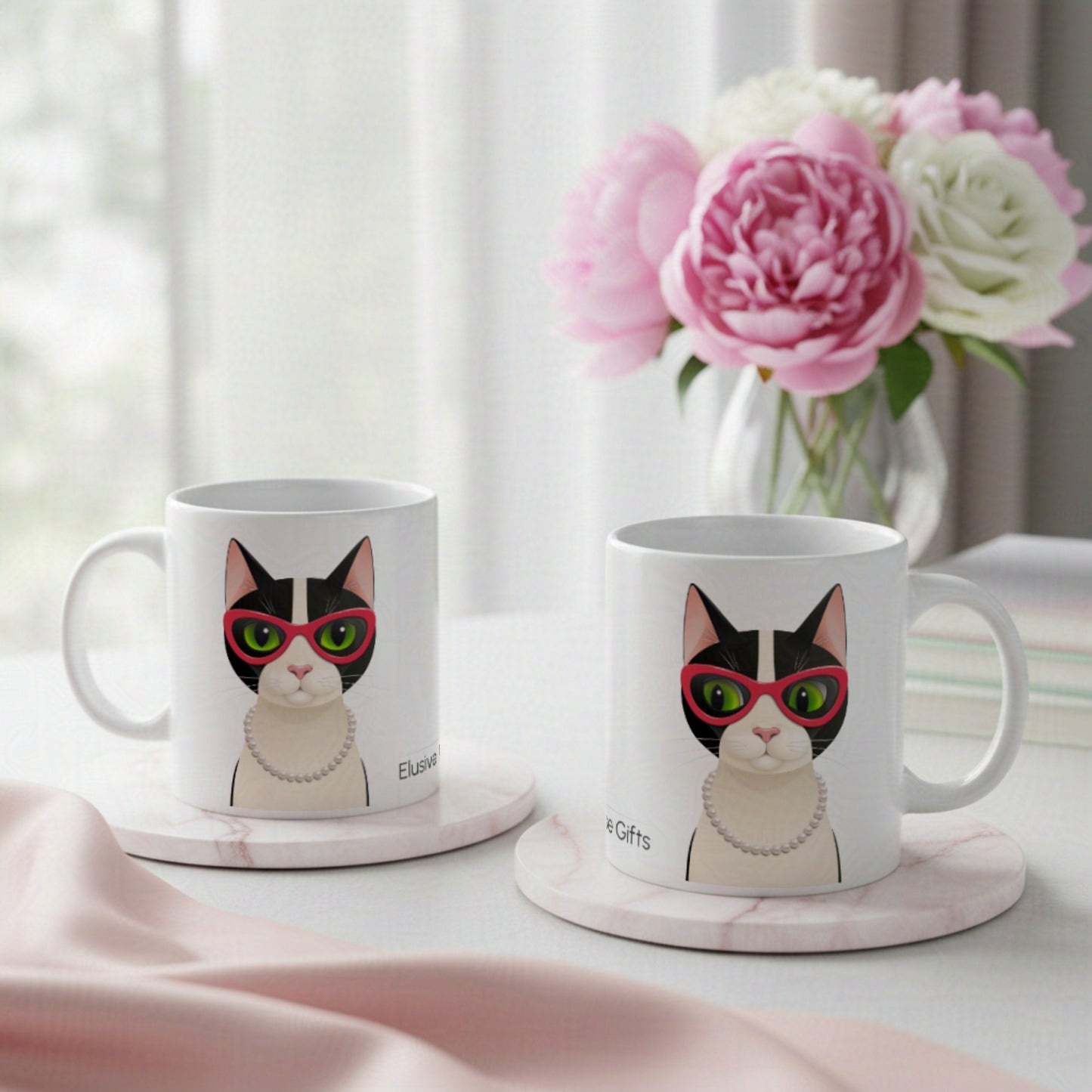 Two mugs with a cat design on a table with flowers in the background