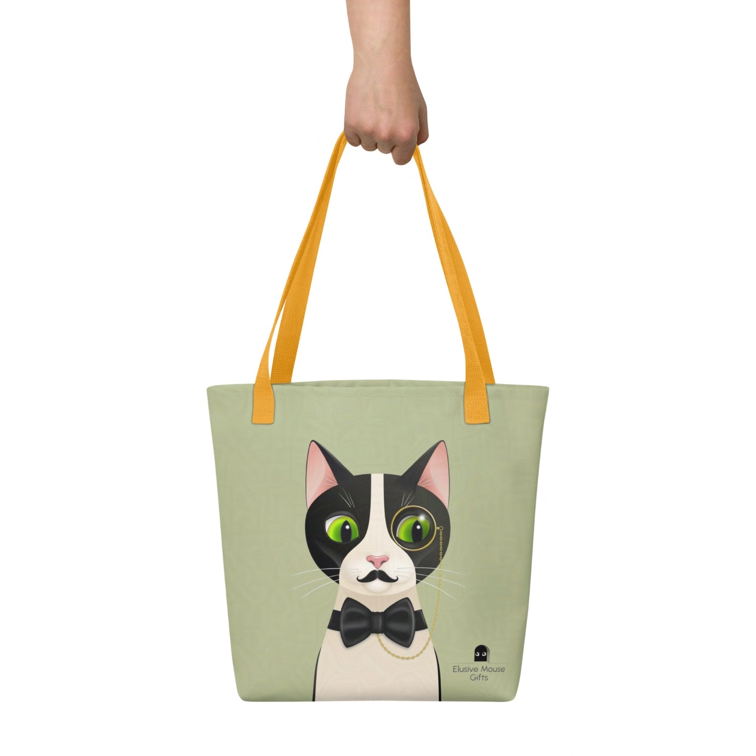 Alfred tote bag shown being carried by hand with the full cat illustration visible, against a sage green background