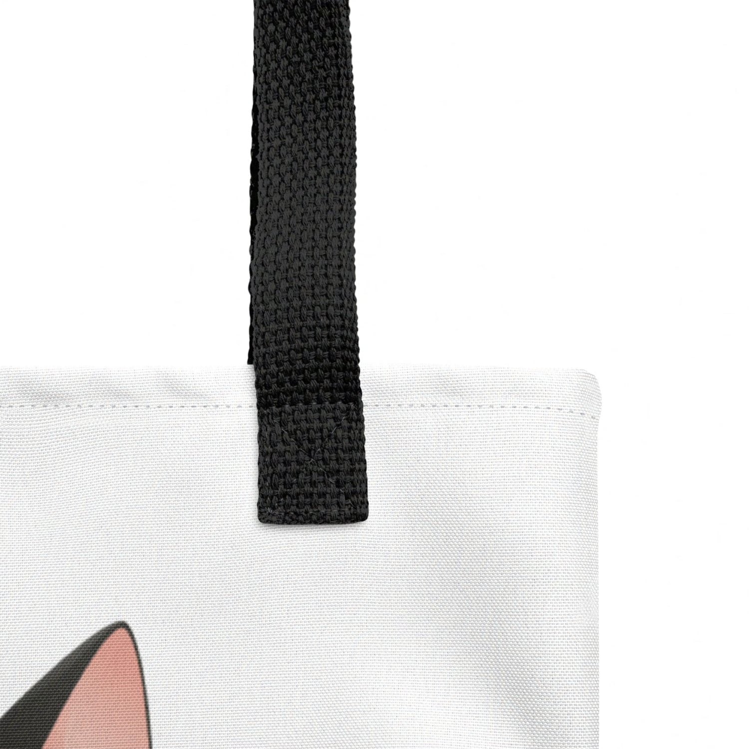 Close-up detail of Freddie tote bag strap join and stitching, cat print visible below against a white background