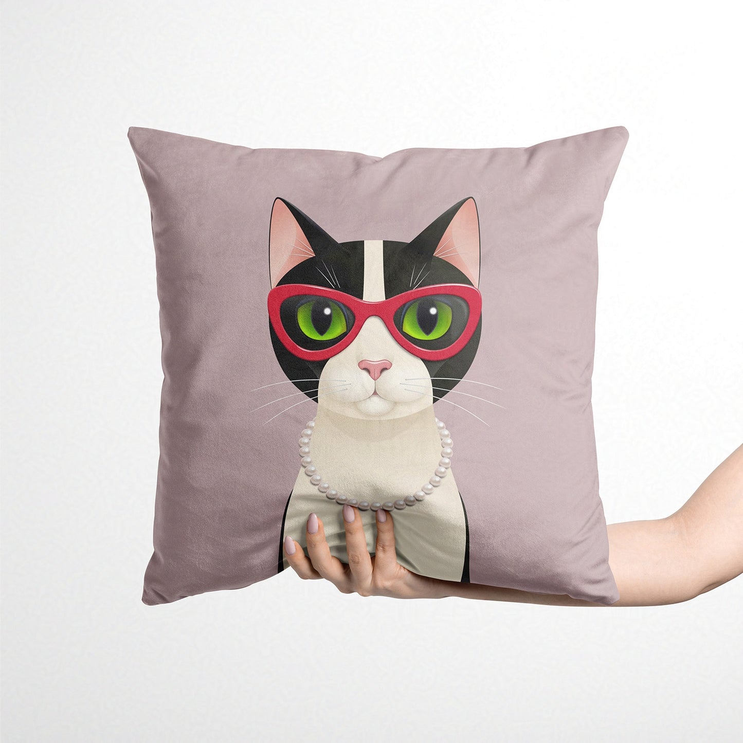 Decorative cushion with a cat design wearing sunglasses held by a hand against a white background