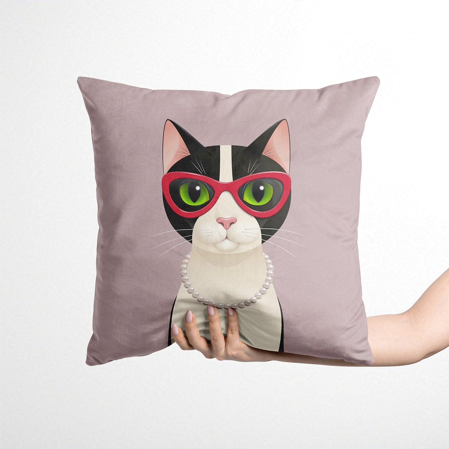 Decorative cushion with a cat design wearing sunglasses held by a hand against a white background