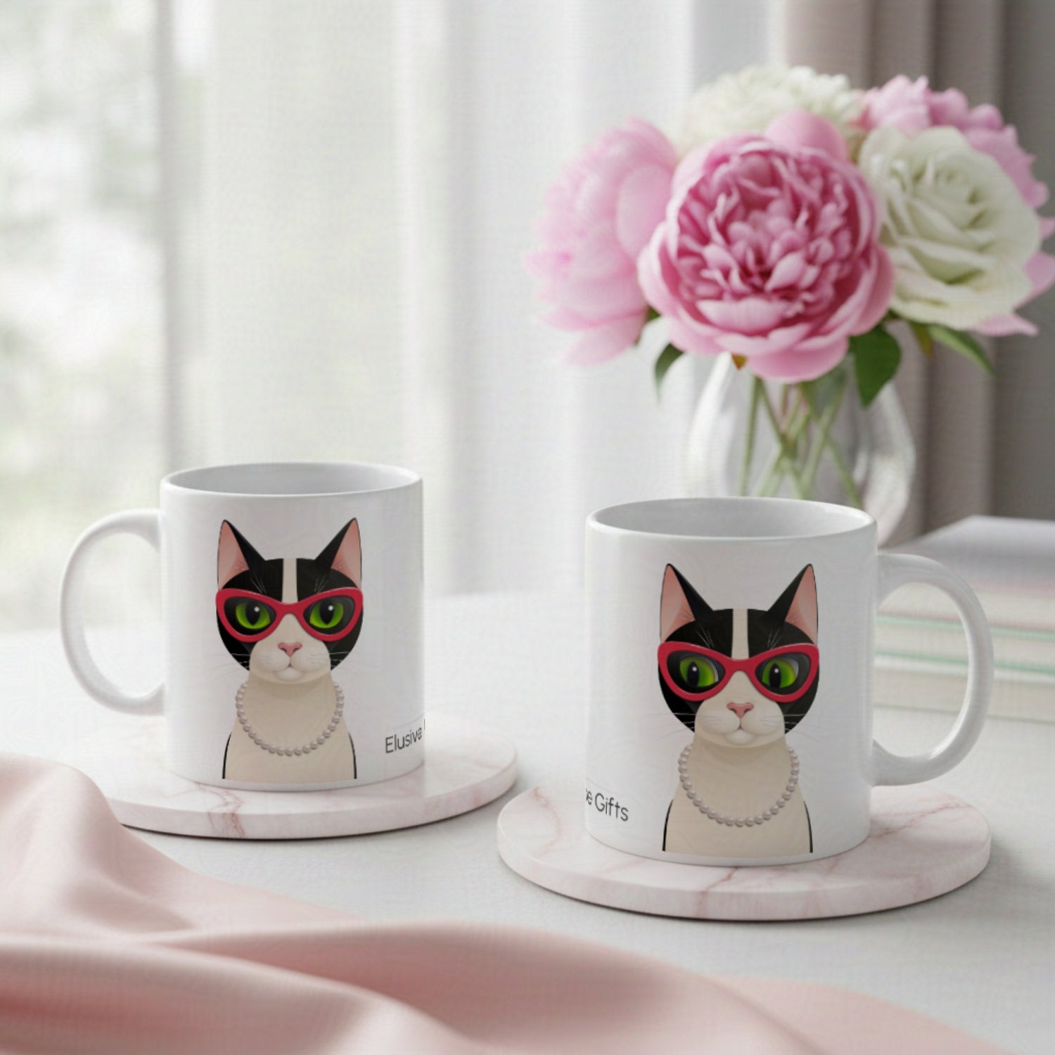 Two mugs with a cat design on a table with flowers in the background