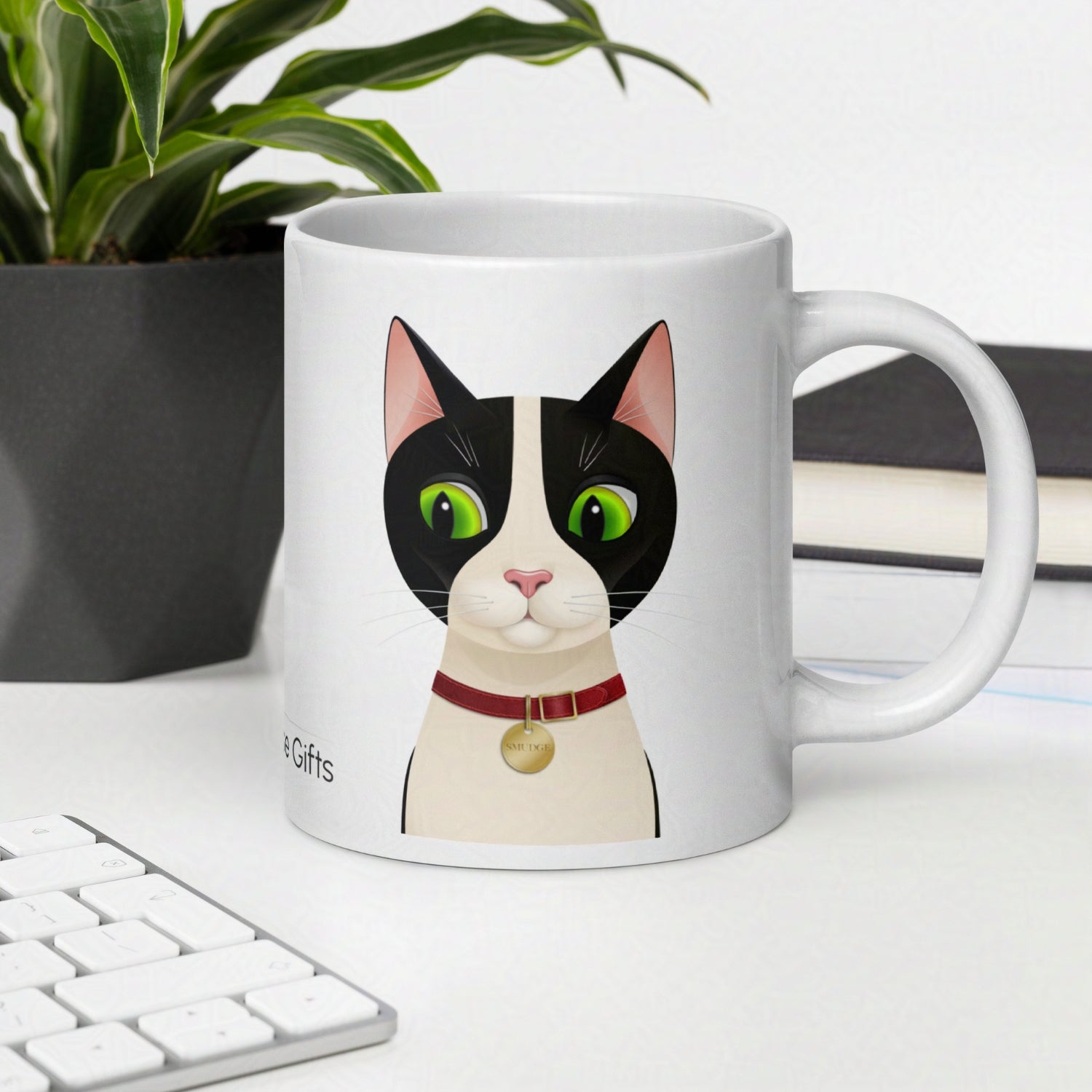 Smudge the tuxedo cat 20oz mug on desk with keyboard and notebooks and plant in the background